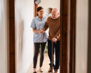 Shot of a young nurse assisting a senior man with a walking stick in a retirement home